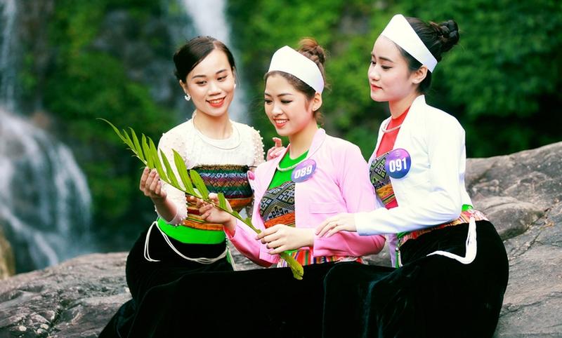 Một người phụ nữ Việt Nam duyên dáng trong tà áo dài truyền thống, đứng cạnh phong cảnh làng quê yên bình